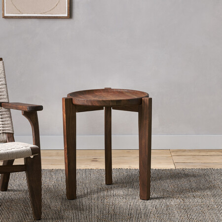 Dark brown acacia wood side table with a circular top and three legs holding a glass a vase 2