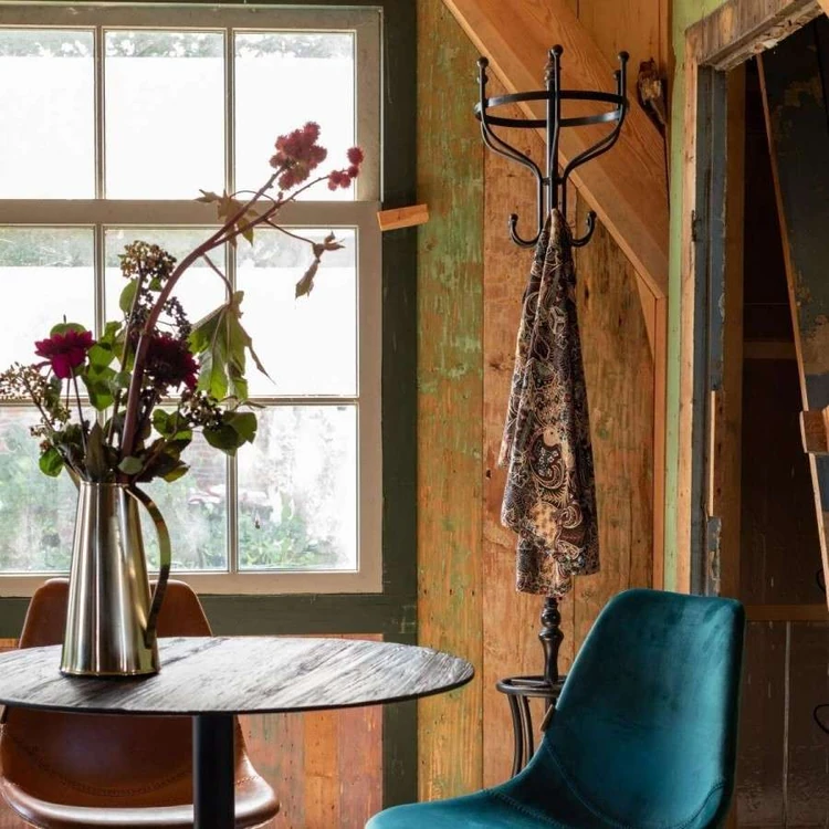 Metal vase full of flowers in a warm wooden room